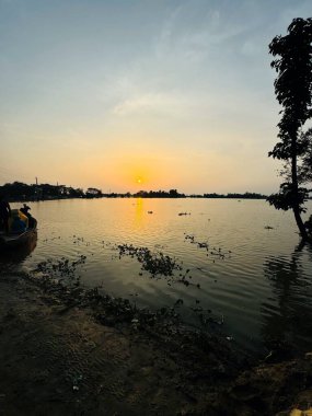 Güneşin sakin bir gölün üzerinde batışının nefes kesici görüntüsü, suyun ve gökyüzünün üzerine sıcak renkler döküyor. Bu çarpıcı sahne romantizm, doğa ve manzara projelerinde kullanılmak için mükemmel..