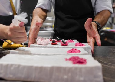 İki şefin birlikte çalıştığı ve gastronomik bir restoranda yemek dağıtırken çekilmiş bir fotoğraf..