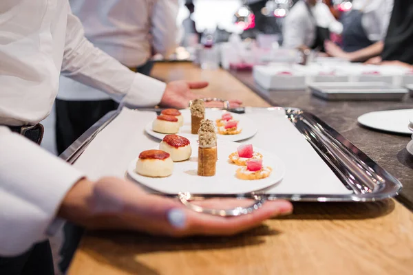 Bir garsonun gastronomik bir restoranda tepsi alırken çekilmiş bir fotoğrafı..
