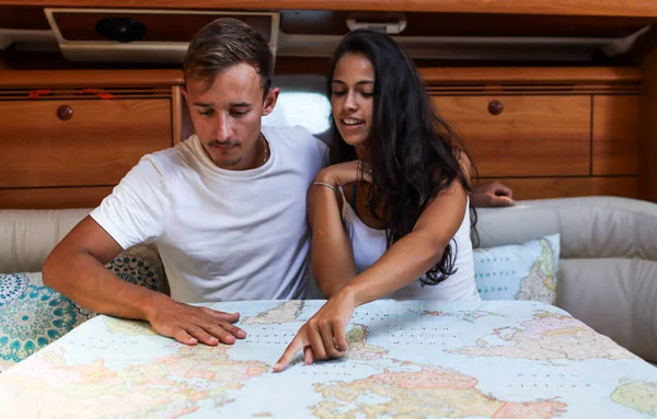一对年轻夫妇在船上寻找他们在地图上的位置 — 图库照片