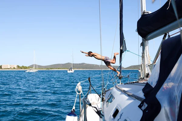 Yelkenliden denize atlayan bir adam, geminin manzarası.