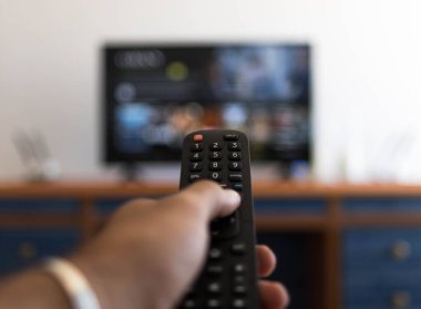 Televizyonda bir film ararken uzaktan kumandayı tutmak