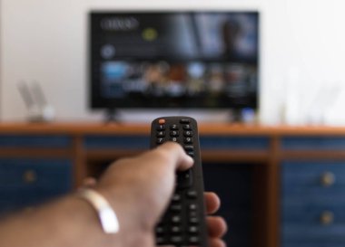 Televizyonda bir film ararken uzaktan kumandayı tutmak