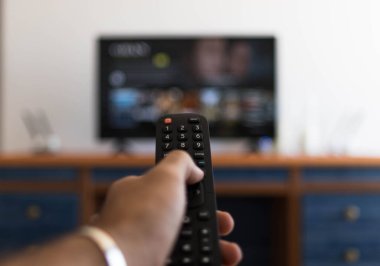 Televizyonda bir diziyi ararken uzaktan kumandayı tutmak