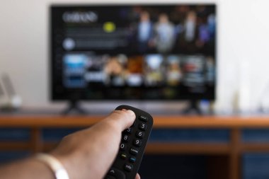 Televizyonda bir diziyi ararken uzaktan kumandayı tutmak