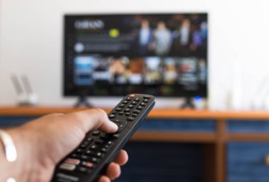Televizyonda bir diziyi ararken uzaktan kumandayı tutmak