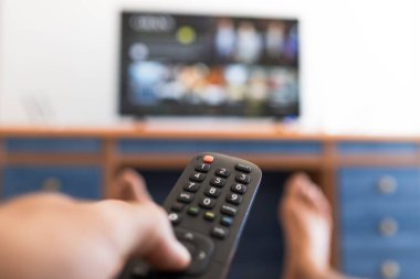 Uzaktan kumandayla TV 'de ayakları yere basan bir film ararken.