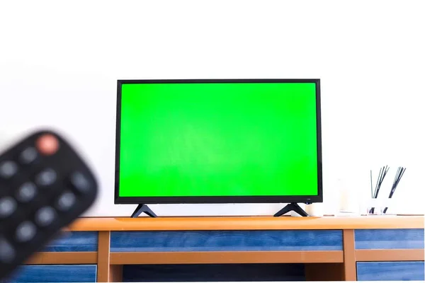 Yanında yeşil ekran ve uzaktan kumanda olan bir televizyonun fotoğrafı..
