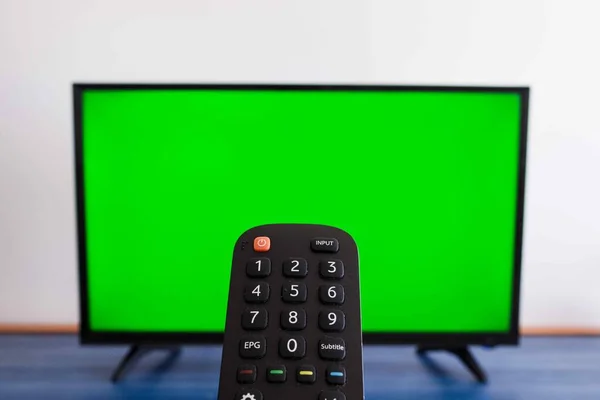 Arka planda yeşil ekran olan uzaktan kumandalı bir televizyonun odaklanmış fotoğrafı