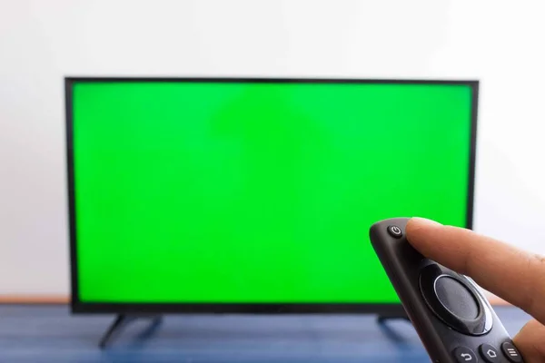 Kézben Tartva Egy Modern Távirányító Vel Zöld Képernyővel Háttérben — Stock Fotó