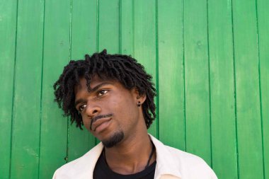 Kıvırcık saçlı genç afro çocuk. Düşünceli. Yeşil arkaplan