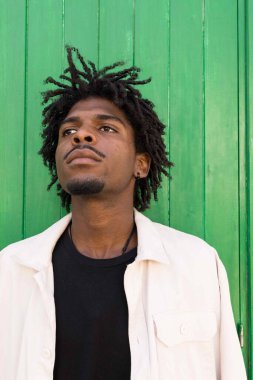 Afro-Amerikalı bir çocuğun dikey fotoğrafı. Saçını oynatırken ve kameraya bakarken..