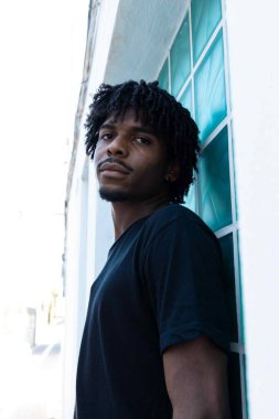 Kameraya bakan kıvırcık saçlı bir afro çocuğun yan fotoğrafı. Dikey fotoğraf