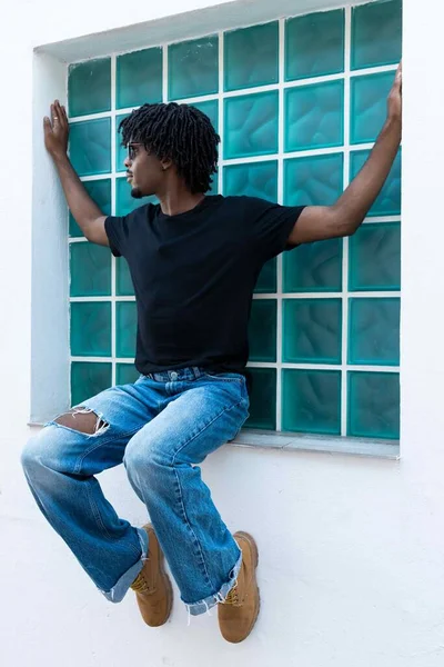 Afro Chłopiec Siedzi Oknie Patrząc Bok Zdjęcie Pionowe — Zdjęcie stockowe