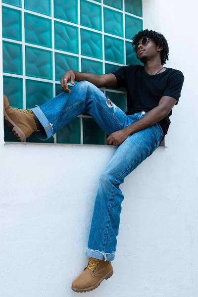 Afro Chłopiec Kręconymi Włosami Relaks Oknie Niebieskim Tle Zdjęcie Pionowe — Zdjęcie stockowe