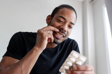 Kırık dişli Latin çocuk her gün aldığı ilaca bakıyor.