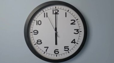 Beyaz Saat Surat 'ın beyaz duvar saatindeki yakın çekimi, oklar 05: 59' dan 6: 00 'ya veya 17: 59: 55' ten 18: 00 'e kadar gösteriyor.