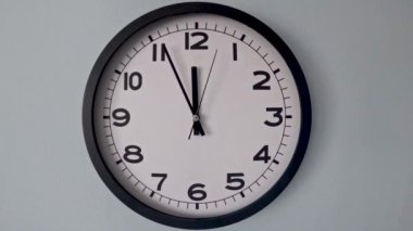 Beyaz Saat Surat 'ın beyaz duvar saatindeki yakın çekimi, oklar 05: 59-18: 55 ya da 17: 55-18: 00' i gösteriyor. Timelaps Yüksek Kaliteli 4K görüntü
