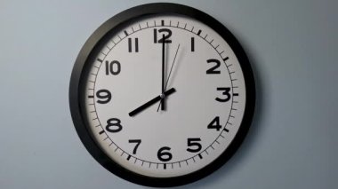 Beyaz Saat Surat 'ın beyaz duvar saatindeki yakın çekimi, oklar 05: 59' dan 6: 00 'ya veya 17: 59: 55' ten 18: 00 'e kadar gösteriyor.