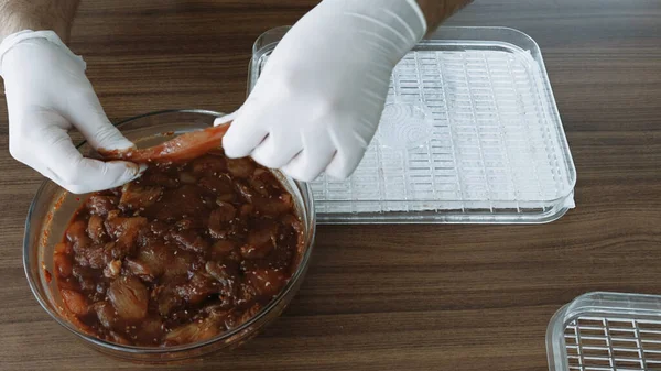 Erkekler eldiven giyip Chiken dilimleri pişirirken susuz kalınca kurutucuda kurutulmuş et yapıyorlar. Yüksek kalite 4k görüntü