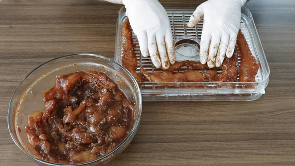 Erkekler eldiven giyip Chiken dilimleri pişirirken susuz kalınca kurutucuda kurutulmuş et yapıyorlar. Yüksek kalite 4k görüntü