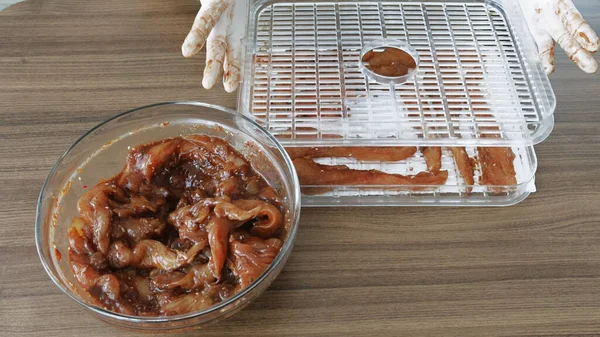 Erkekler eldiven giyip Chiken dilimleri pişirirken susuz kalınca kurutucuda kurutulmuş et yapıyorlar. Yüksek kalite 4k görüntü
