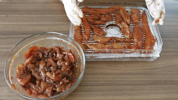 Erkekler eldiven giyip Chiken dilimleri pişirirken susuz kalınca kurutucuda kurutulmuş et yapıyorlar. Yüksek kalite 4k görüntü