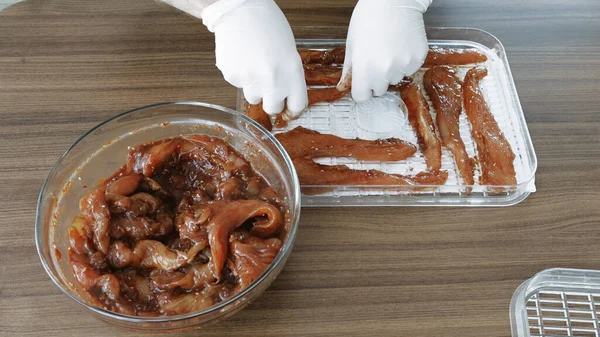 Erkekler eldiven giyip Chiken dilimleri pişirirken susuz kalınca kurutucuda kurutulmuş et yapıyorlar. Yüksek kalite 4k görüntü