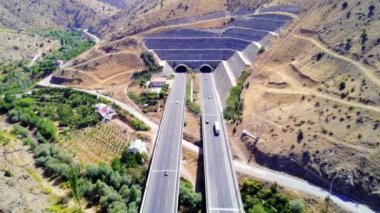 Dağlardan geçen iki şeritli bir otoyolun havadan görüntüsü. Dağ yolu. İnanılmaz yeşil manzaranın hava görüntüsü, yol trafiği yüksek kalitede 4K görüntü.