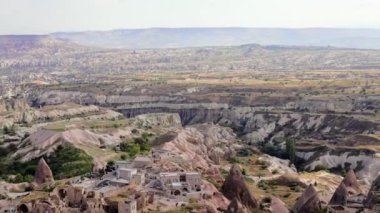 Uchisar Kalesi 'nin parlak mavi gökyüzünün karşısındaki kayanın manzarası. Türkiye 'nin Nevsehir ilinin Kapadokya ilçesinin Uchisar mağara kasabasının tepesinde bayrak sallanıyor. UNESCO Dünya Mirası sitesi. Yüksek kalite 4k görüntü