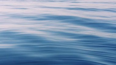 Soyut hava denizi yaz okyanusu günbatımı doğa arka planı. Su yüzeyindeki küçük dalgalar güneşten gelen altın bokeh ışıklarıyla bulanıklaşır. Tatil, yüksek kalite 4K görüntü