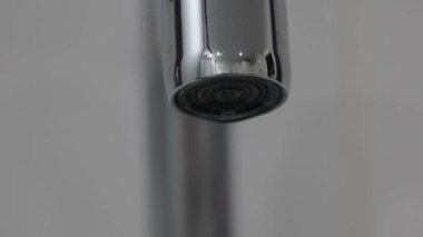Metal su musluğunun beyaz arka plandaki aşırı yakın çekimi izole edilmiş. Düşen damlalar yavaş çekimde can sıkıcı oluyor. Yüksek kalite 4k görüntü