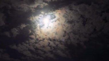 Zaman atlaması, deniz üzerinde yükselen dolunayı yakalar, sürüklenen bulutlar tarafından çerçevelenir, kıyı şehrinin arka planına karşı, büyüleyici bir gökyüzü manzarası yaratır.