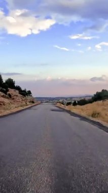 Türkiye 'nin dağlık arazisinde bir karayolu gezisi, açık mavi yaz gökyüzünde batan güneşin altında bir aksiyon kamerasıyla sürmenin heyecanını yakalıyor. Yüksek kaliteli görüntüler