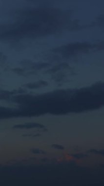 Akşam vakti gökyüzü hızlanırken, büyüleyici bir bulut bulutu zıt yönlerde yatay hareket ederek bulutlu günbatımının arka planına karşı büyüleyici bir tablo çizer..