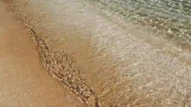 berrak okyanus dalgaları, sakin suyu temsil ederek, yavaşça kıyıya vurur. Sakin suyun kuma değdiği sakin anlar. Sakin suyun ritmi kıyı şeridini sakinleştiriyor.