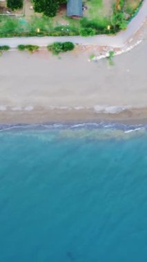 Kıyı şeridi boyunca süzülen bir dron, sahili aydınlatan çarpıcı bir deniz manzarası yakalıyor, bozulmamış doğa, kristal berrak turkuaz deniz, ve kumlu sahil, cezbedici bir yolculuk yeri yaratıyor..