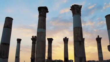 Günbatımı antik harabelere çarpıcı bir ışık tutuyor. Eski Yunan sütun sütunları silueti kalıntıları kadim gökyüzünün alevli görüntüsü altında duruyor. Antik kalıntıların arasında sütunlar sonsuz ihtişam yankılanıyor..