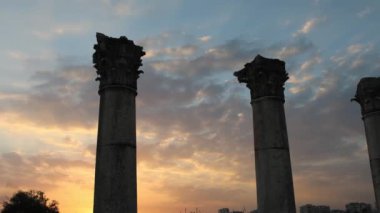 Günbatımı, Mersin 'in Pompeliopolis kentindeki bir sıra Yunan sütununun üzerine altın ışığı örtüyor. Bu kadim sütunlar, tarihe ciddi bir şekilde tanıklık ediyor. Sütunlar arasında uzun gölgeler oynar, eski hikayelerin yankıları.