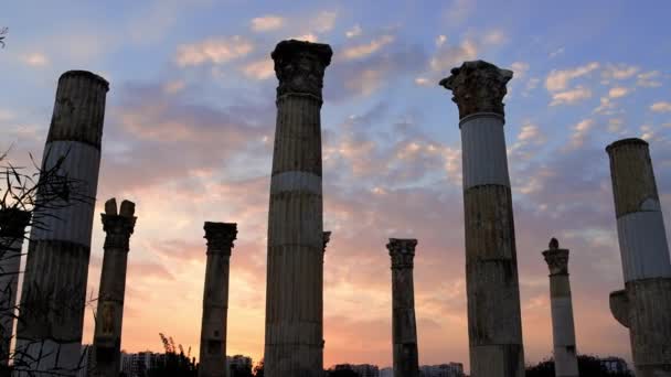 劇的な夕日が古いコロネード 歴史的なギリシャのシーンを背景にしています コロネードは 古代の概念的な視界の激しい空の下で遺跡を破壊する 古い寺院の壮大さをエコーするコロネードスタンド — ストック動画