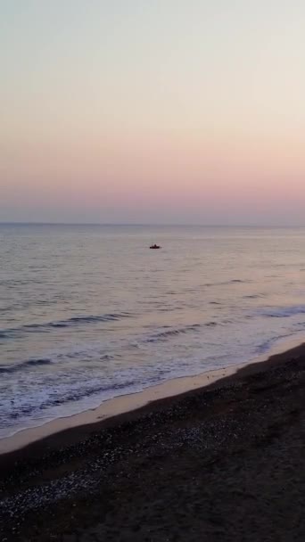 ドローンは日没で海辺の町を撮影し 黄金色の色合いを基調としています 日没は夜の町と対照的に水を反射する 海の上のトランキルサンセット 町のシルエットを受け入れる — ストック動画