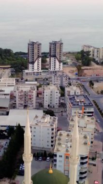Gün batımında denizin arka planına karşı şehir merkezinde iki minaresi olan küçük bir cami. Silah bir İHA 'dan ateşlenmiş. İki minaresi olan bir camiden uzaklaşıyor. İslam kavramı.