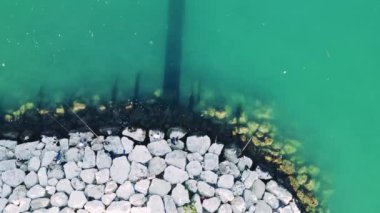 Erdemli İskelesi 'ndeki balıkçılar, plastikle kirlenmiş bir denize bakıyor. Plastikle kaplanmış deniz güzelliği çevresel hasarı vurguluyor. Denizdeki plastik kirliliği deniz yaşamına onarılamaz zararlar veriyor..