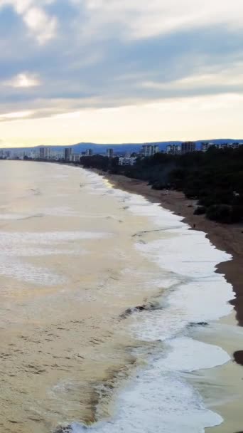 Gün Batımında Deniz Kıyısındaki Kasabaya Ulaşan Dalgaların Üzerinde Bir Dron — Stok video