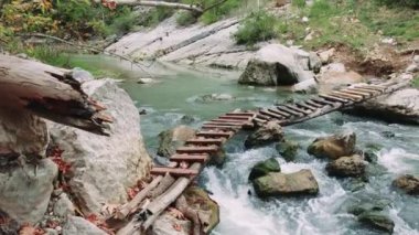 Tahta köprü temiz dağ nehrini geçer, ekolojiyi gösterir. Temiz nehir ahşap köprünün altından akar, ekoloji korunur. Ekoloji, tahta köprünün altındaki temiz sularda görülür. Yüksek kalite 4k görüntü