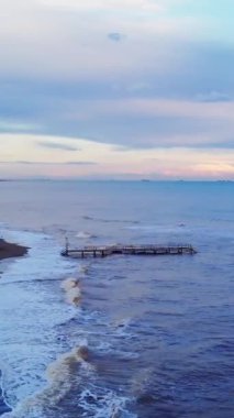 İnsansız hava aracı Akdeniz şehrinde süzülüyor, gün batımında sahil şeridi güzelliğini yakalıyor. Hava aracı görüntüleri: dalgalar kıyı şeridini okşadı, şehir zeminini. Günbatımı insansız hava aracı görüntüsü: sakin kıyı şeridi canlı şehir hayatıyla buluşuyor.