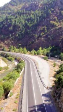 Hava yolu manzarası, yazın dağ yolu. Yolculuk macerası, dağlık arazide gezinti tutkusu. Yolculuk, dağların arasından geçen otoban yılanları, hava manzarası. Yüksek kaliteli görüntüler