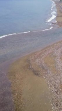 Drone gün batımında kumlu sahilden geçerek nehri takip ediyor. Nehir sahil boyunca kıvrılır, İHA denizdeki yolunu yakalar. Nehirlerin kumsaldan denize yolculuğunun günbatımı manzarası, hava manzarası..