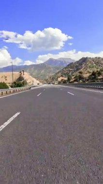 Dağ yolu gezisi, arabalar birinci şahıs manzarası, manzarada kıvrılan siyah asfalt. Dağ yolunda yolculuk, çarpıcı manzaralar. Dağ yolunda araba gezintisi, derin seyahat deneyimi.