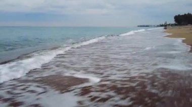 İnsansız hava aracı kumsalda alçaktan uçar, gün batımında dalgaları yakalar. Çarpıcı sahil şeridi, dalga manzarası. Kıyı şeridinin hava görüntüleri, dalga desenleri. Büyüleyici sahil şeridi, alacakaranlıkta dalga sahneleri..